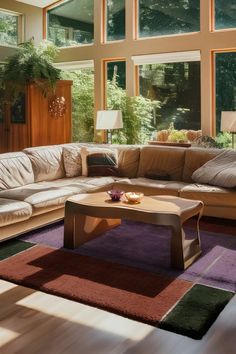 a living room filled with lots of furniture and large windows overlooking the trees in the distance