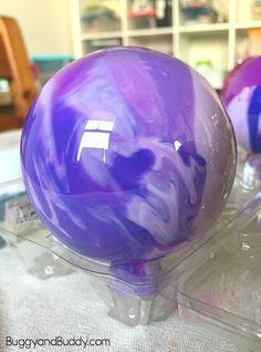 two purple balls sitting on top of a plastic container