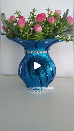 a blue vase filled with pink roses on top of a white table next to a wall