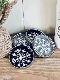 three black and white plates sitting on top of a wooden table next to a vase