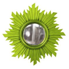 a green sunburst shaped mirror hanging on the wall