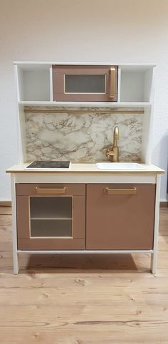 a toy kitchen with marble counter tops and wooden flooring in a room that has hardwood floors