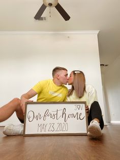 a man and woman kissing in front of a sign