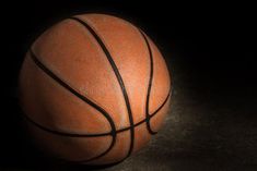 a basketball sitting on top of a black table next to a white ball with brown lines