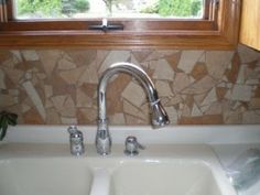 a kitchen sink with two faucets under a window