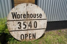 a wooden sign that says warehouse 350 open on it in front of a metal building