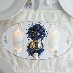 the table is set with white plates and silver utensils, candles, and napkins