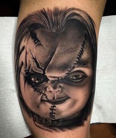 a man's leg with a creepy clown face tattoo on his arm and shoulder