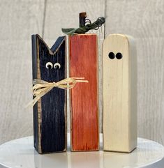 three wooden pieces with eyes and noses tied to each other on top of a white table