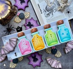 halloween decorations and cookies are arranged on a table with an open book in the background