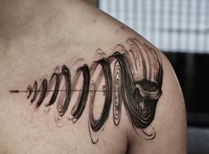 a man's shoulder with an abstract tattoo design on the left side of his chest