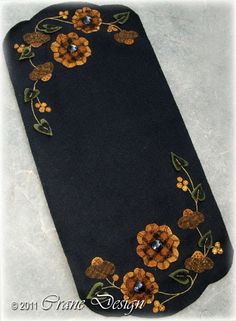 a black case with orange and yellow flowers embroidered on the side, sitting on a white surface