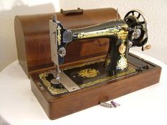 an antique sewing machine sitting on top of a white table next to a brown case