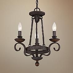 an iron chandelier with three lights hanging from it's center and two small candles in the middle