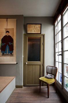 a yellow chair sitting in front of a doorway next to a painting on the wall