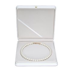 a pearl necklace in a white box with a gold clasp on the front and side