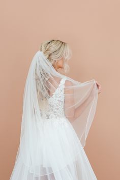 the back of a bride's wedding dress, with her veil draped over her shoulder