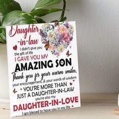 a daughter in law card on a table next to a potted plant and figurine