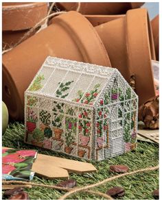 a small house made out of seeding beads on the ground next to potted plants