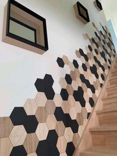 a wooden staircase with black and white hexagonal tiles on the wall next to it