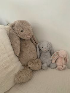 three stuffed animals sitting on top of a bed