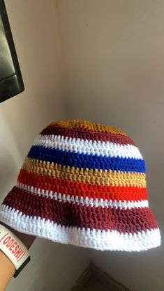 a multicolored crocheted hat hanging from the ceiling next to a wall