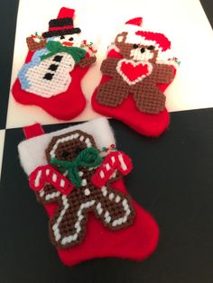 three christmas stocking ornaments are sitting on a table