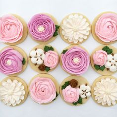 twelve decorated cookies with pink and white frosting flowers on them, arranged in rows