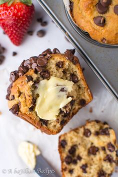 chocolate chip muffins with butter on top and strawberries next to them in the background