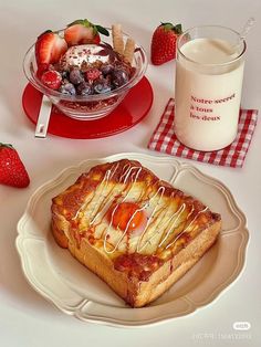 a plate topped with cake next to a bowl of strawberries and a glass of milk