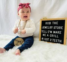 a baby sitting next to a sign that says rob the jewelry store tell'em make me a grill got 2 teeth