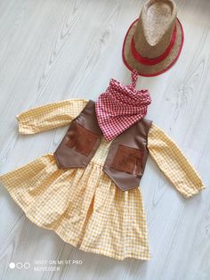 Adorable Baby Cowgirl Costume Set - Western Gingham Dress with Vest, Hat, and Bandana 🤠 Yeehaw! Get ready for some Wild West fun with this adorable Baby Cowgirl Costume Set. Perfect for little explorers who love adventure, this Western-themed outfit is as stylish as it is comfortable. The set includes a charming yellow and white gingham dress👗, offering a classic country look, paired with a brown faux leather vest🎽 featuring fun fringe details. To complete the authentic cowgirl look, a red ch Outfit With Dress, Hat And Bandana, Dress With Vest, Baby Cowgirl, Boys Costumes, Cowgirl Outfit, Cowgirl Look, Faux Leather Vest