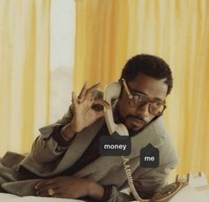 a man sitting on a bed talking on a phone with the words money me in front of him