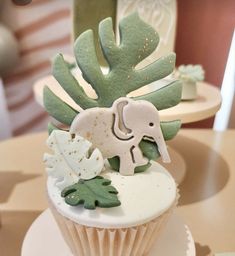 a cupcake decorated with green leaves and an elephant