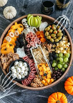 a platter filled with halloween food and snacks on top of a table next to two pumpkins