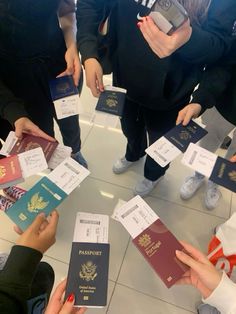 several people standing around each other with their passport cards in front of them and one person holding a cell phone