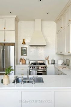 a kitchen with white cabinets, stainless steel appliances and marble counter tops is pictured in this image