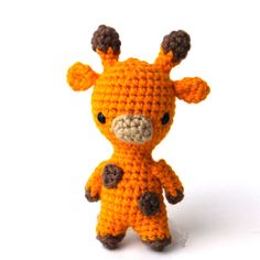 an orange crocheted giraffe stuffed animal sitting on top of a white surface