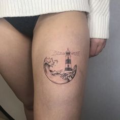 a woman's thigh with a lighthouse tattoo on it