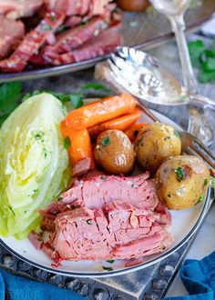 a plate full of meat, potatoes and carrots on a table with silverware