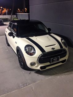 a white and black car parked in front of a building at night with lights on