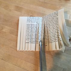 an open book sitting on top of a wooden floor next to a pair of scissors