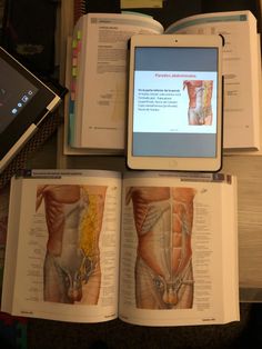 an open book with pictures of the human body on it and a tablet next to it