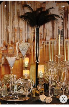 a table topped with lots of glass vases filled with flowers and candles next to a tall palm tree