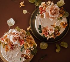 two cakes decorated with flowers and leaves on plates