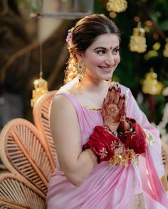 a woman in a pink dress is holding her hands together and smiling at the camera