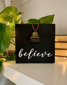 there is a sign that says believe with a bell hanging from it's side