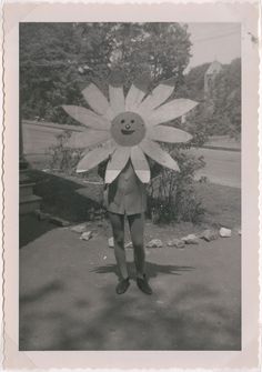 an old black and white photo of a person holding a large flower