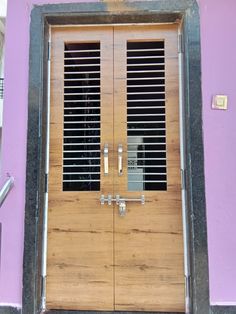 a wooden door with metal bars on the top and bottom, in front of a purple wall