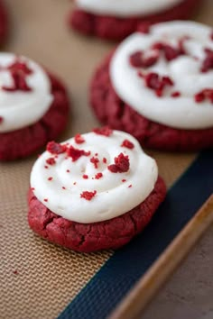 red velvet cookies with white frosting and sprinkles on a baking sheet